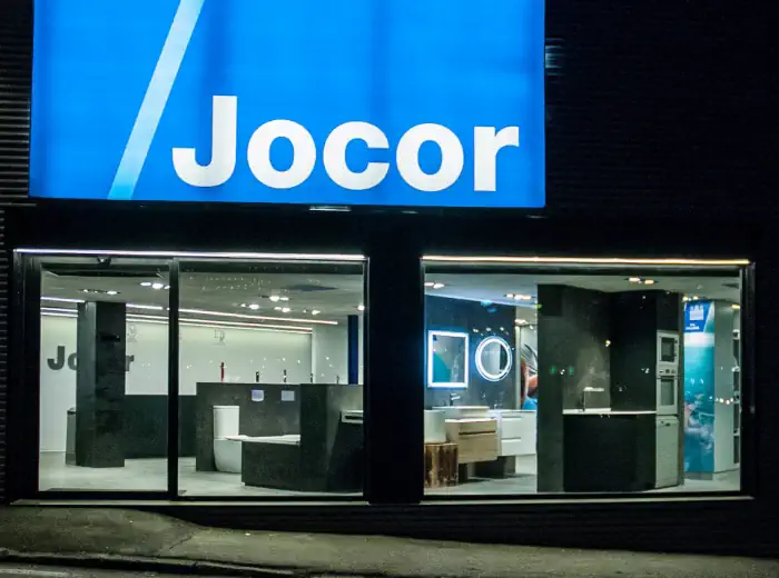 Façana exterior de la botiga Jocor amb el logotip il·luminat i espai d’exposició de banys i instal·lacions a Andorra.
