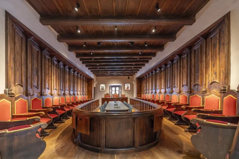 Sala de sessions de la Casa de la Vall a Andorra la Vella amb mobiliari històric, sostres de fusta i arquitectura patrimonial.