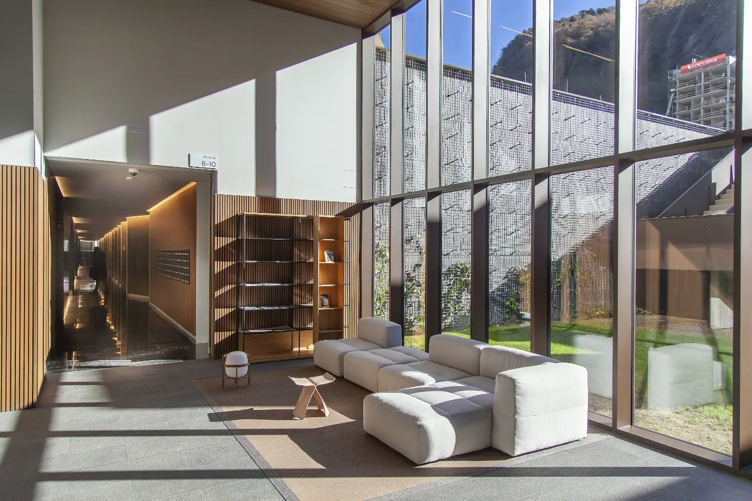 Vestíbul d’entrada d’edifici residencial amb grans finestrals, llum natural i disseny interior contemporani a Andorra la Vella